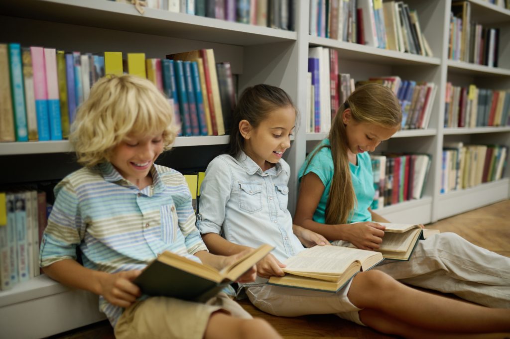 boy two girls sitting floor reading books