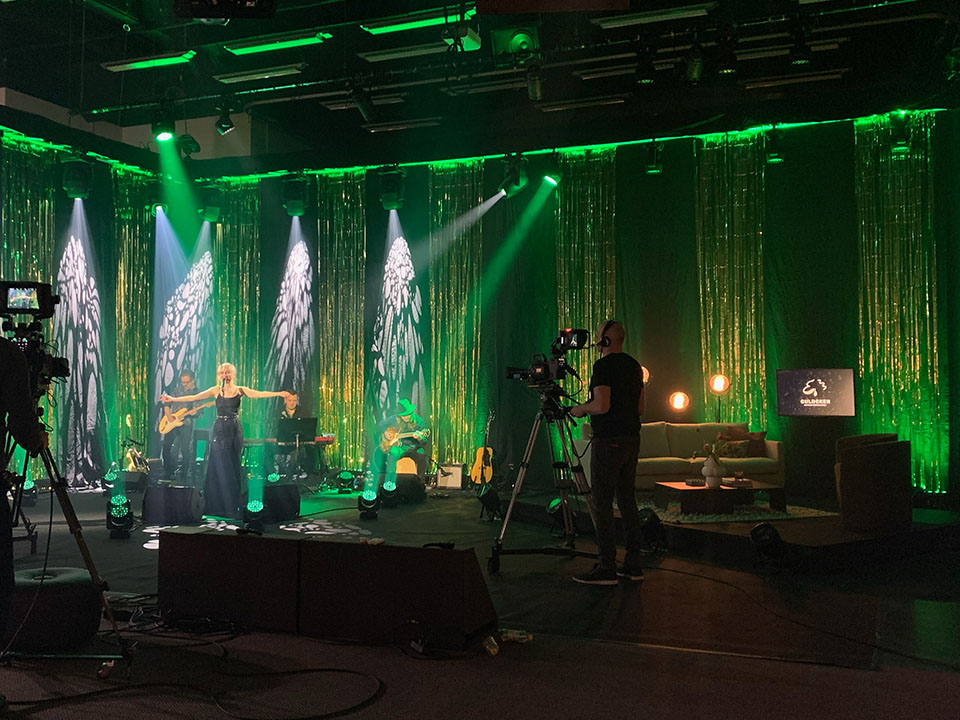 En kvinna som sjunger med sitt band i en tv-studio